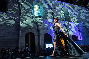 Femme défilant en robe de soirée dans un décor sombre au Palais