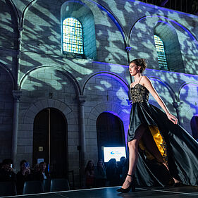 Femme défilant en robe de soirée dans un décor sombre au Palais