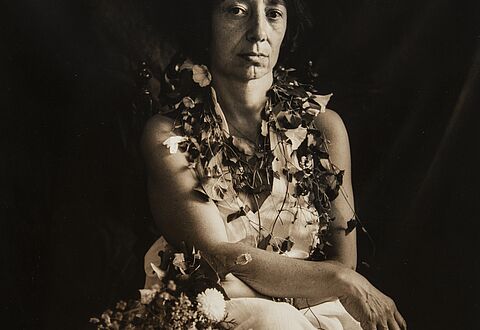 Photo en noir et blanc d'une femme en robe blanche avec du lierre autour du cou