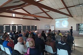 photo de personnes réunies dans une salle devant un conférencier