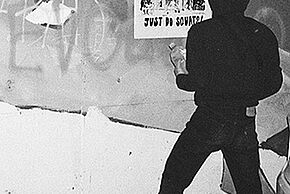 Photo en noir et blanc d'un homme devant une affiche