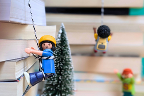 Des figurines escaladent des piles de livres.