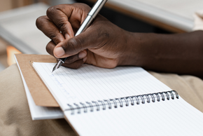 Une personne écrit avec un stylo dans un cahier.